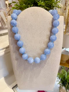 Blue beaded necklace on a mannequin bust with a blurred background